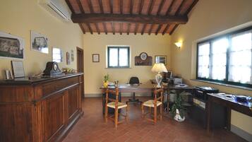 A dining area with a wooden table and chairs, a kitchen counter, and a window with curtains.