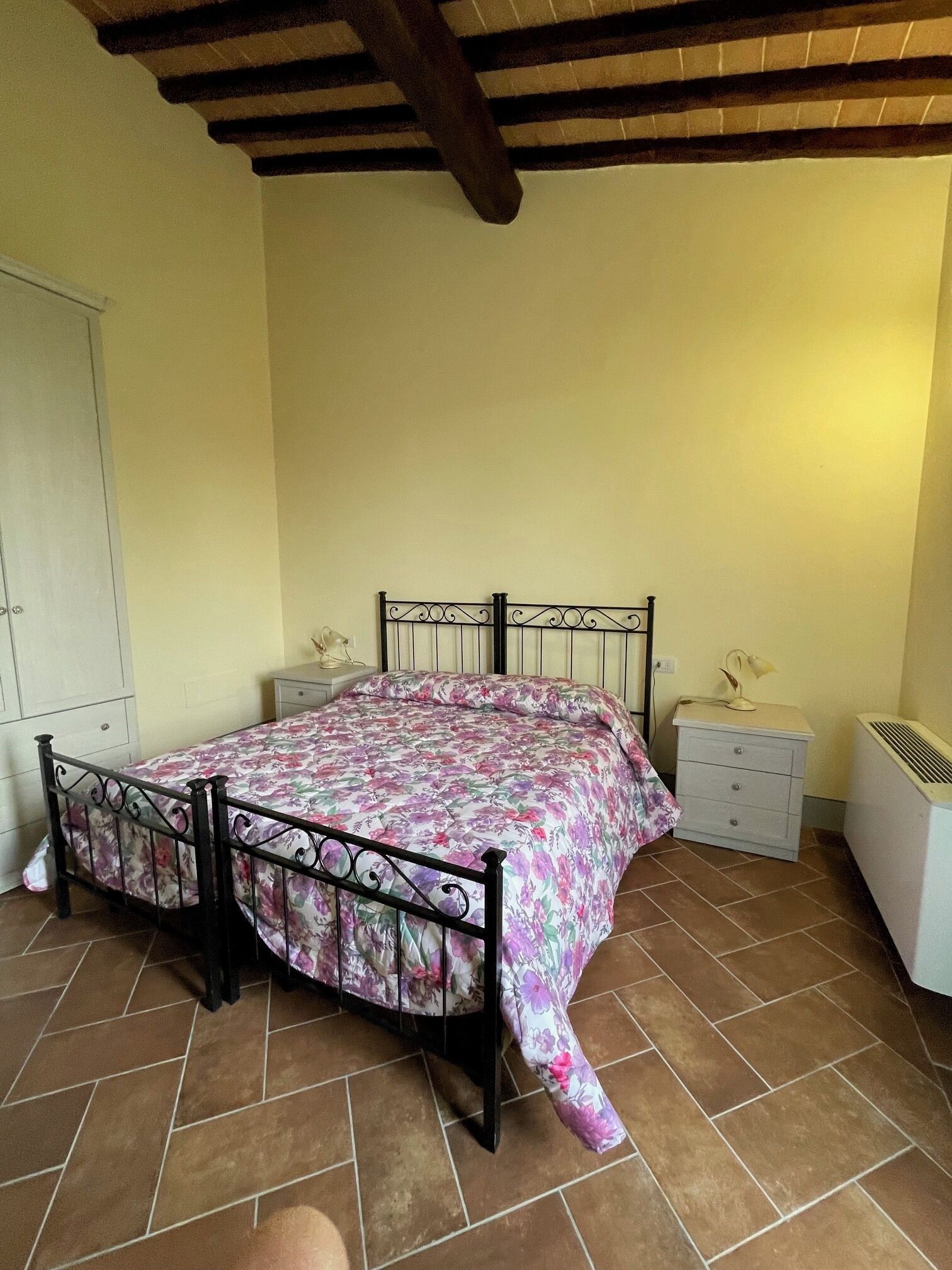 Une chambre à coucher comprenant un lit, des tables de chevet, une armoire et un radiateur.