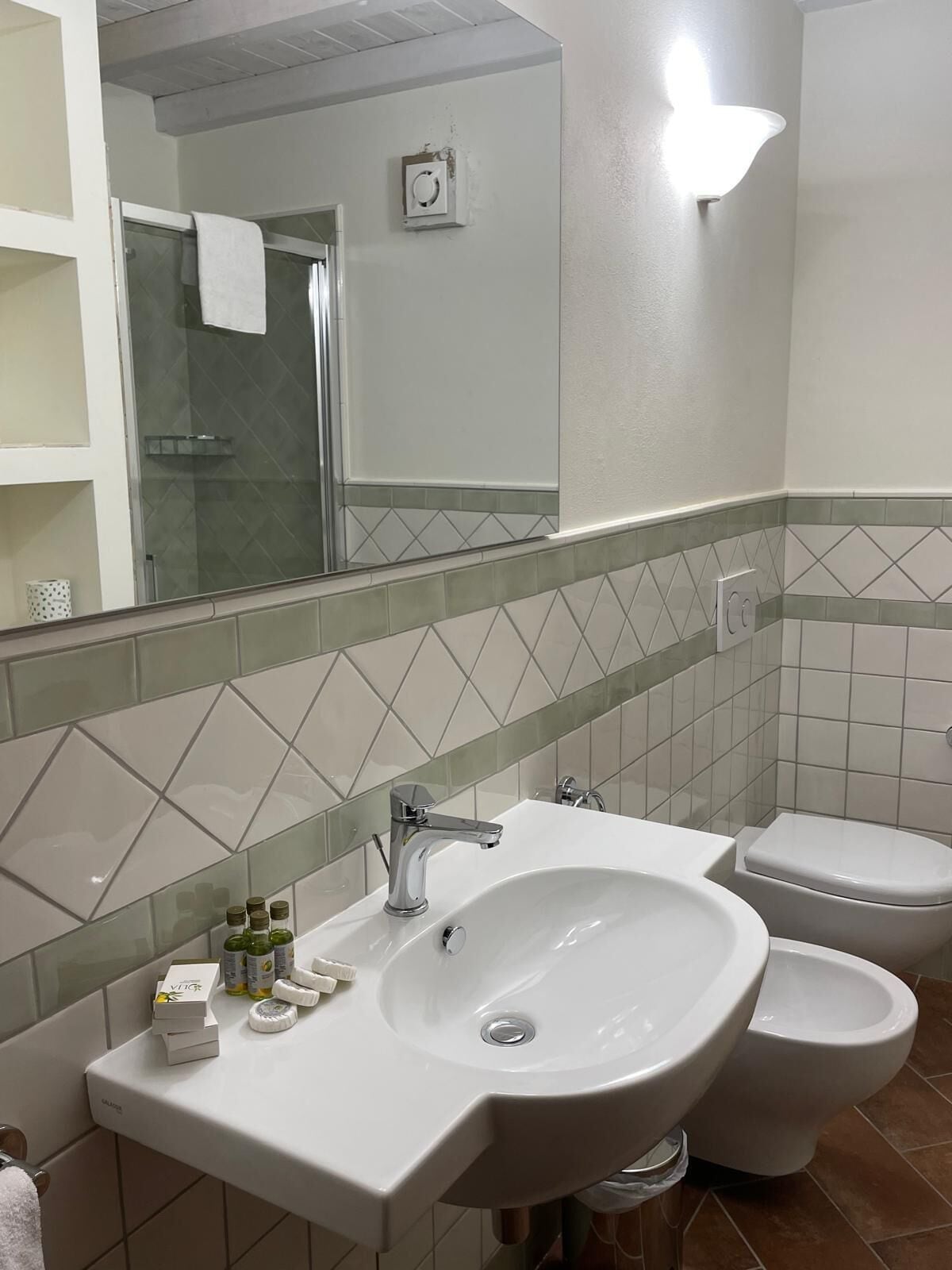 A bathroom with a white sink, two toilets, and a glass shower enclosure.