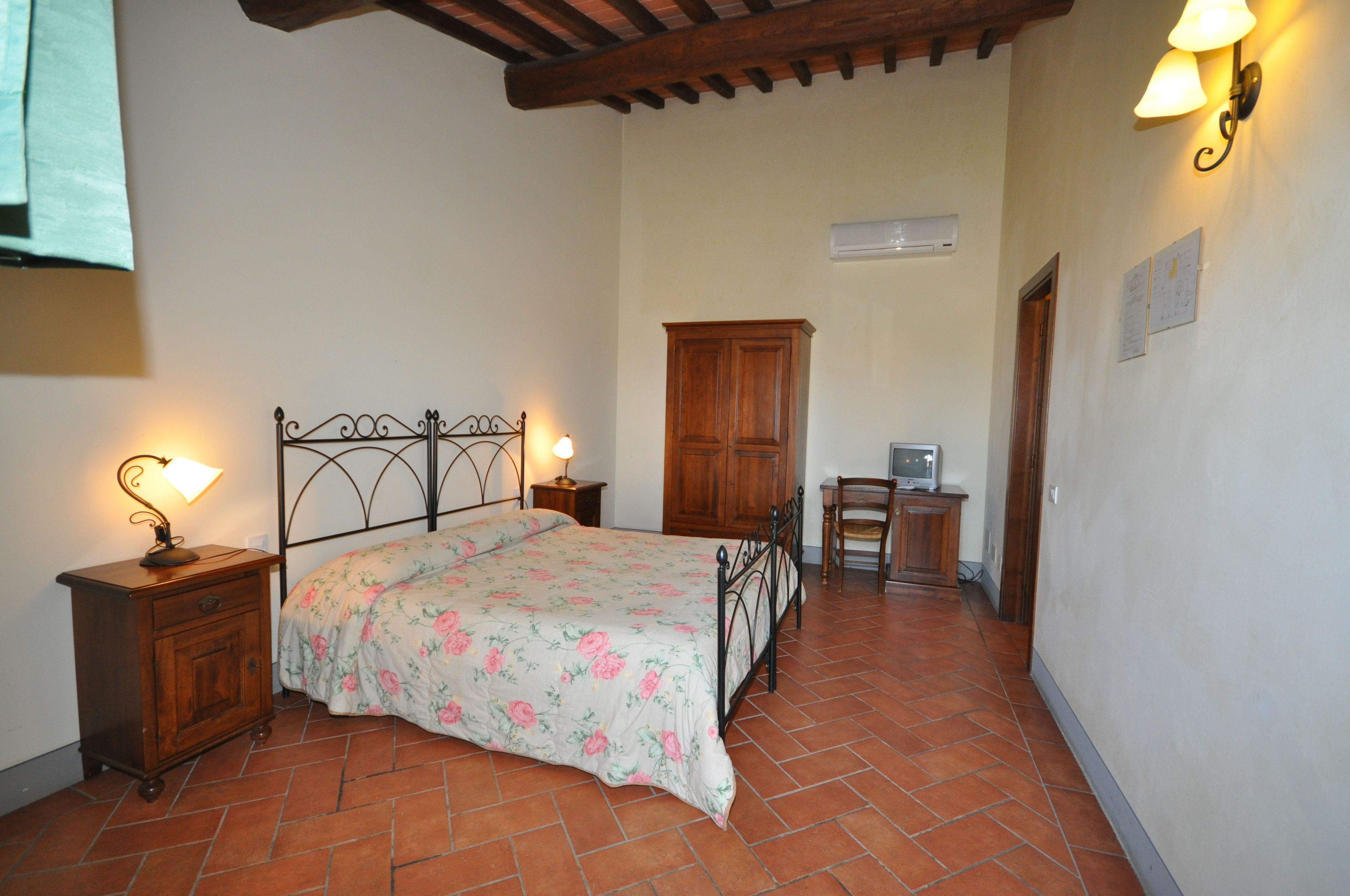 A bedroom with a bed, nightstands, a wooden cabinet, a desk, and a chair.