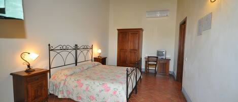 A bedroom with a bed, nightstands, a wooden cabinet, a desk, and a chair.