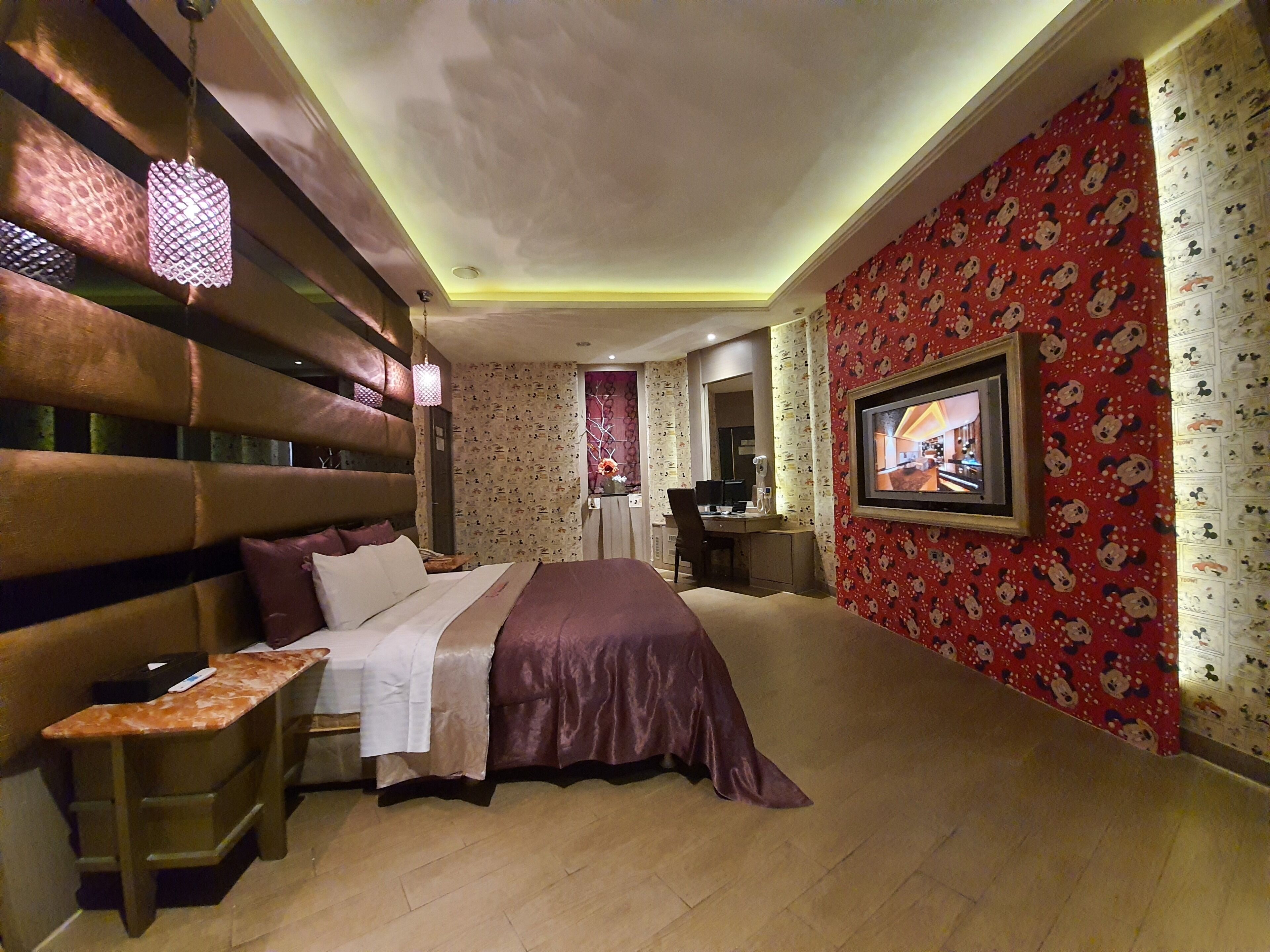 Une chambre avec un grand lit, un bureau et une télévision.