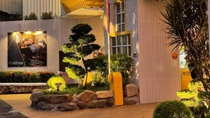 A multi-story building with balconies, a well-maintained garden, and a visible water tank. - Jin Sha Motel (Taichung)
