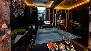 A modern bar area with a large sink, a television, and a variety of fruits and bottles on the counter. - Jin Sha Motel (Taichung)