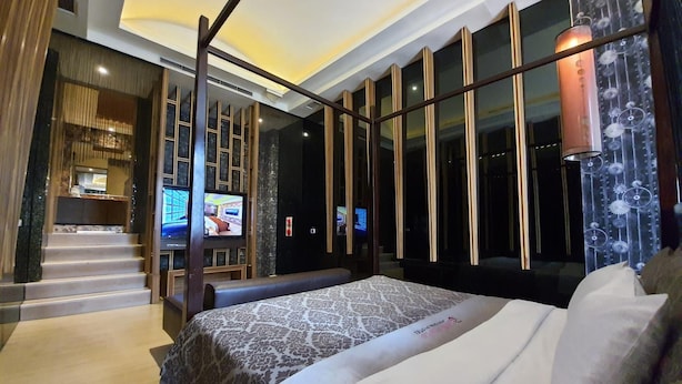 A modern hotel room with a large bed, a TV, and a view of the interior. - Jin Sha Motel (Taichung)