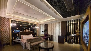 A modern bedroom with a large bed, a sofa, a round coffee table, and a TV screen. - Jin Sha Motel (Taichung)
