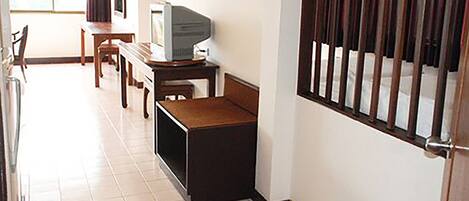 A small, compact room with a television on a wooden stand, a small table, and a chair.