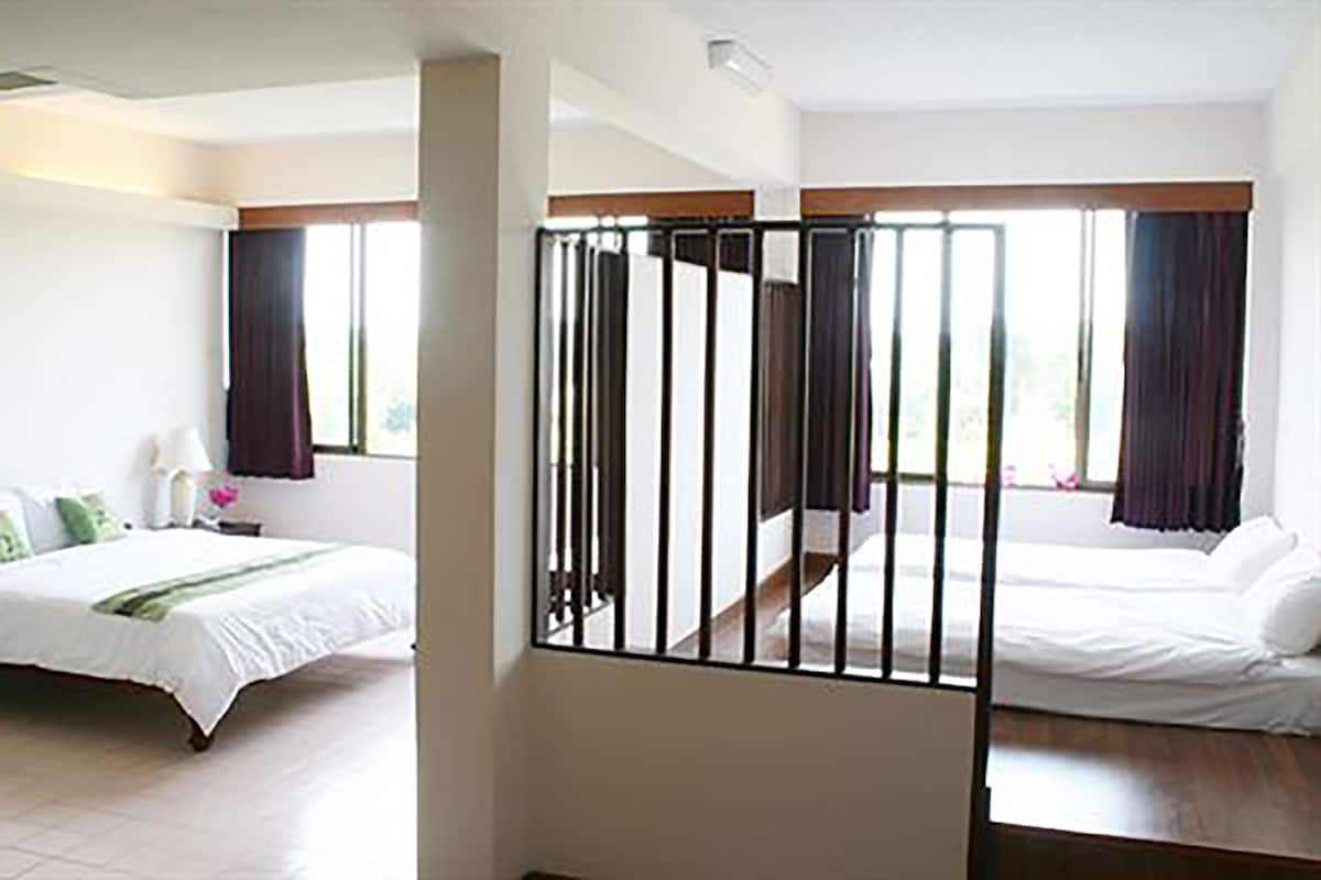 A hotel room with two beds, a balcony, and large windows with curtains.