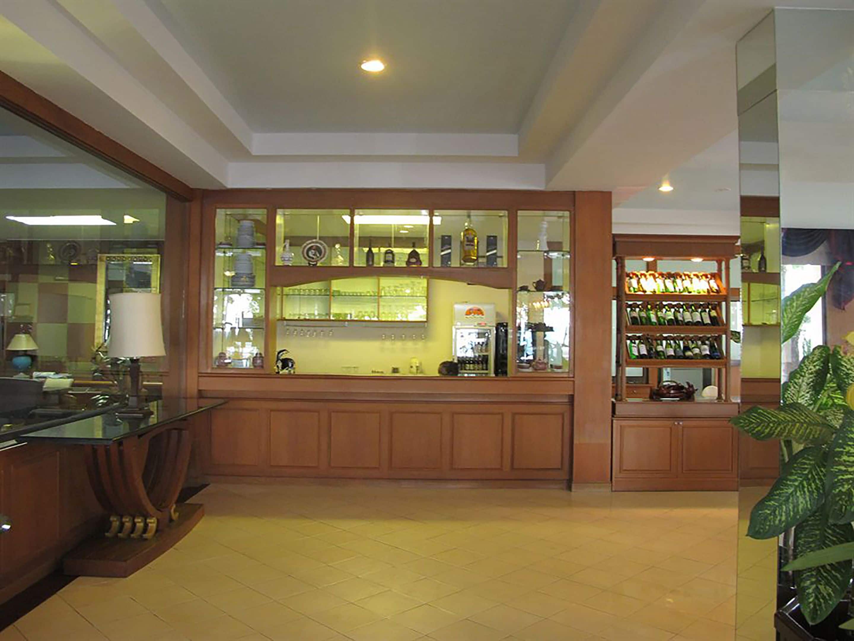 A bar area with wooden cabinets and shelves displaying bottles.