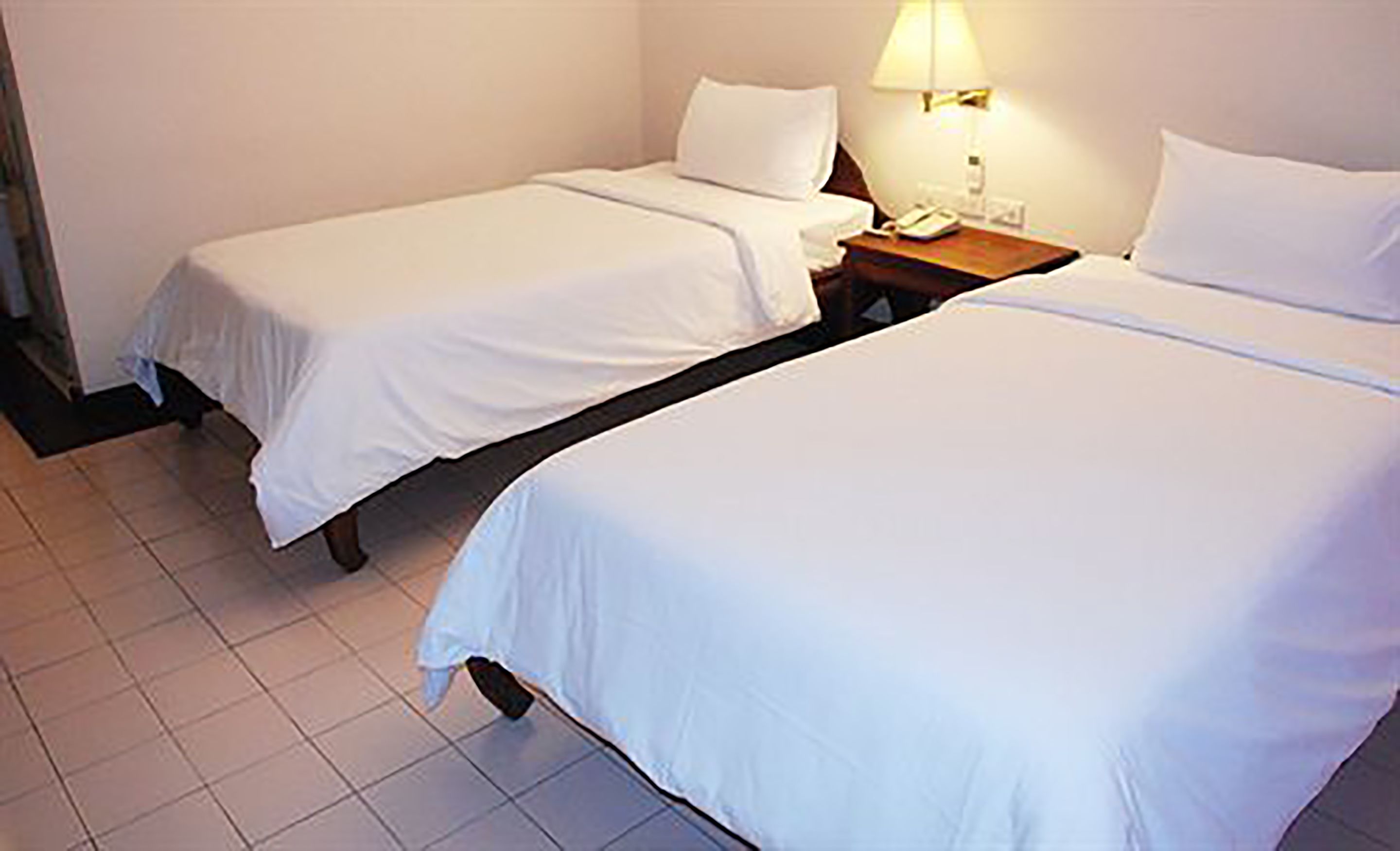 Two single beds with white linens in a hotel room.