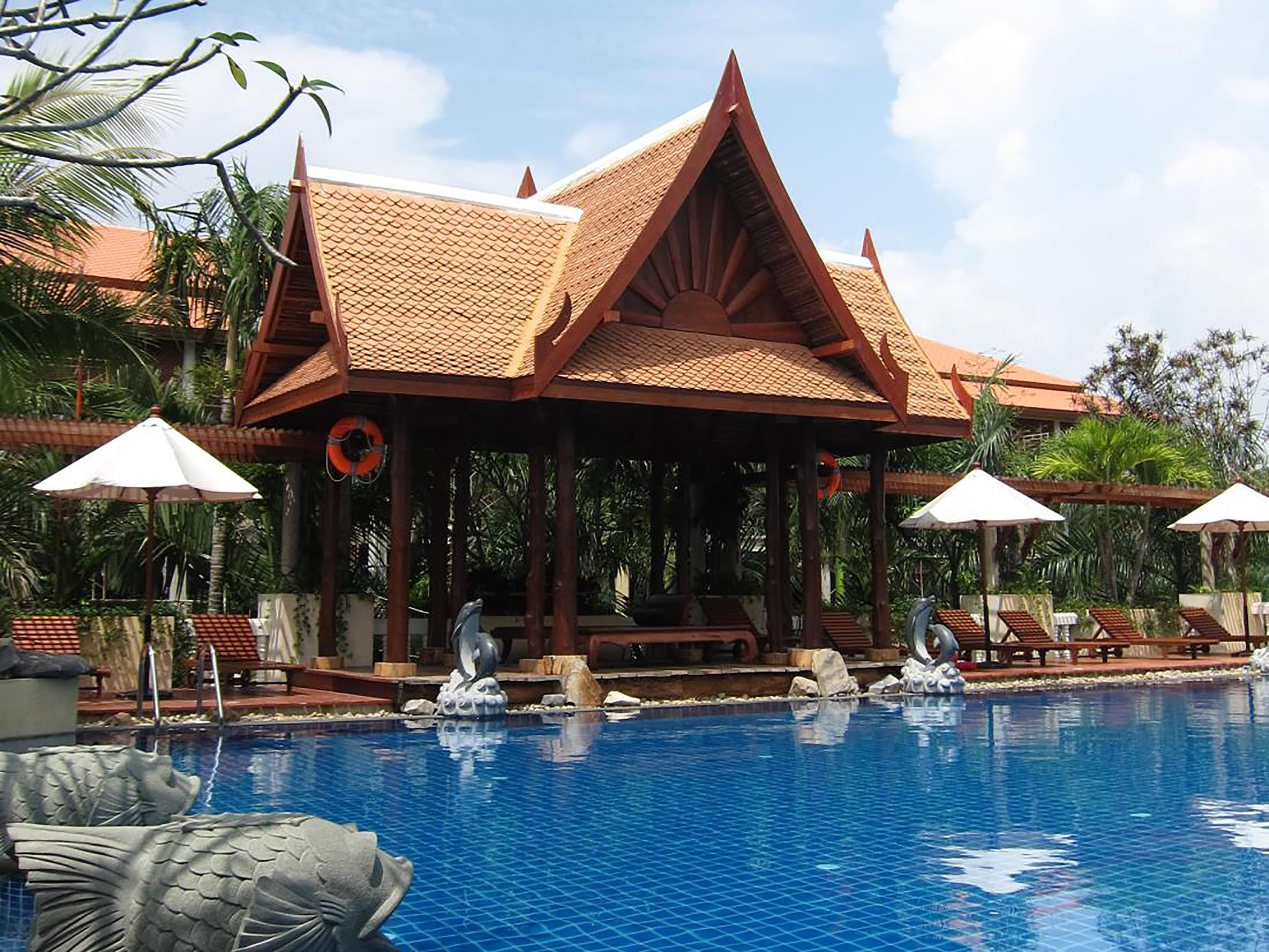 A pool area with a traditional pavilion, lounge chairs, and a lifebuoy.