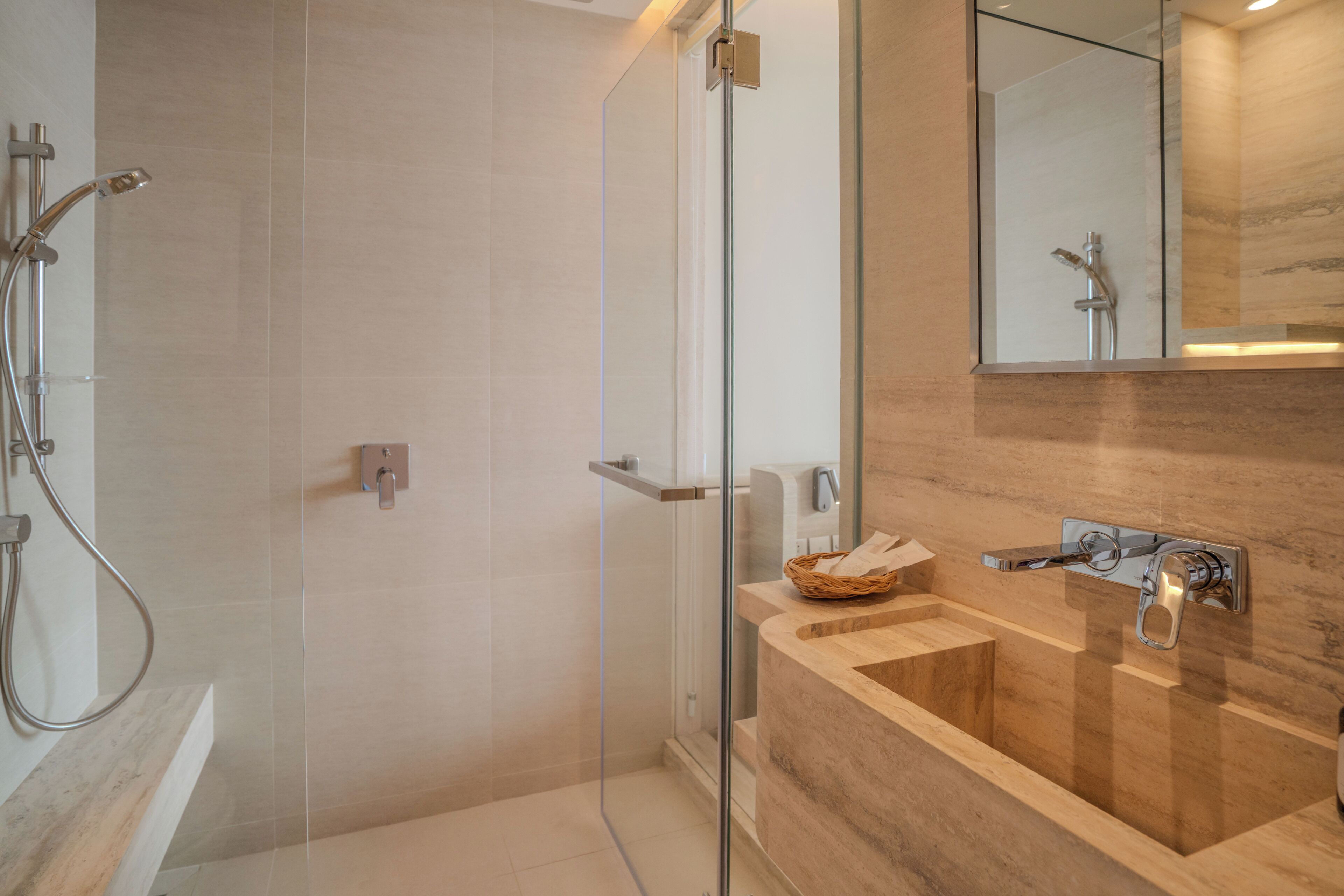 A modern bathroom with a glass-enclosed shower, a wooden vanity with a sink, and a mirror above the vanity.