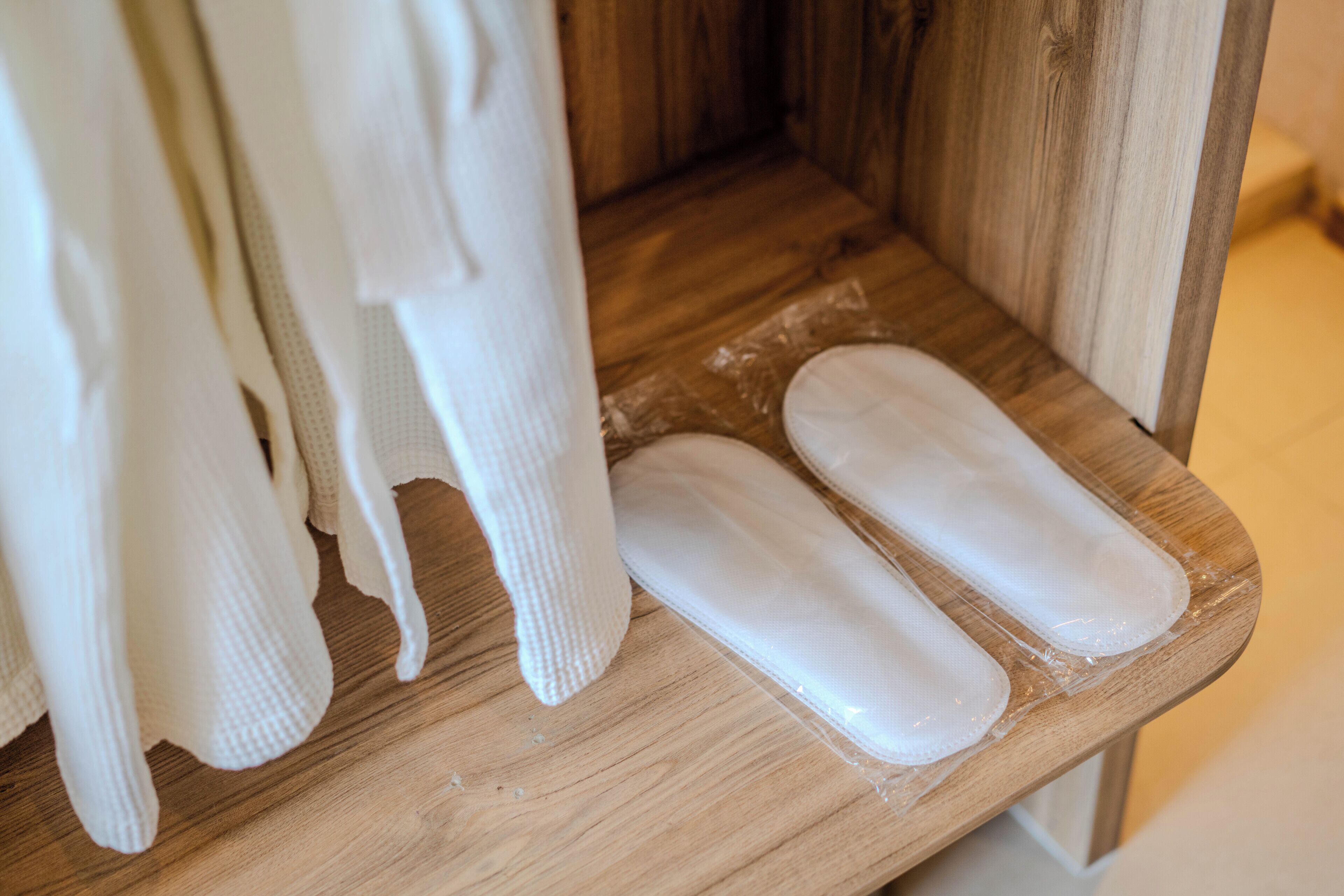 A wooden shelf with white fabric items and a pair of white pads.