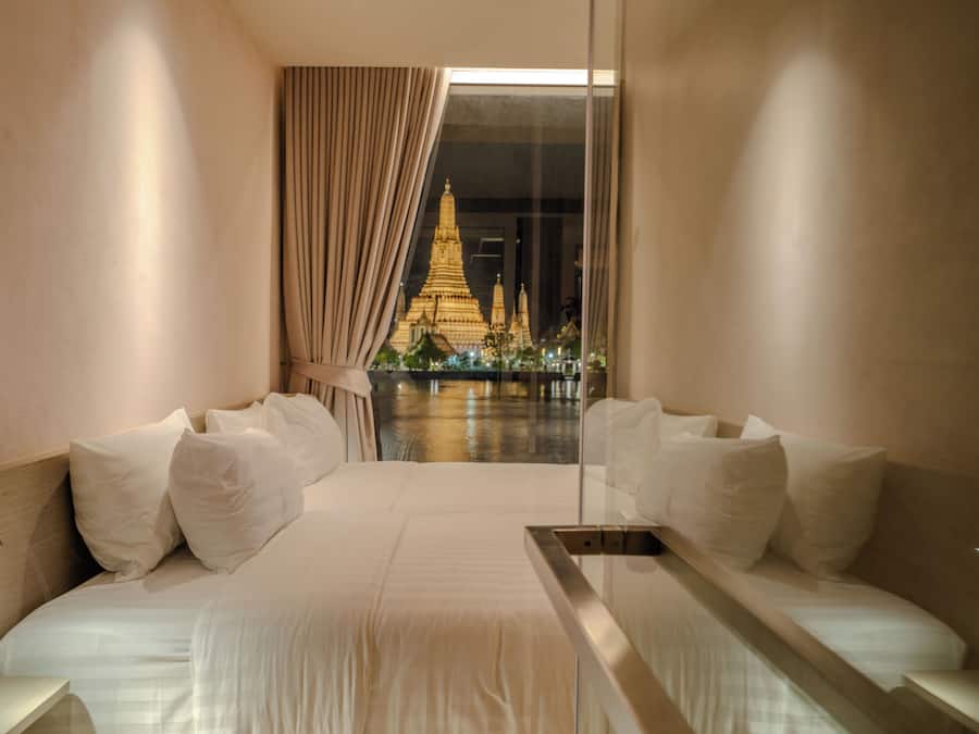 A hotel room with a large bed, curtains, and a view of a temple.