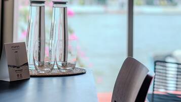 A table with two glasses and a menu, a chair, and a view of a temple through a window.