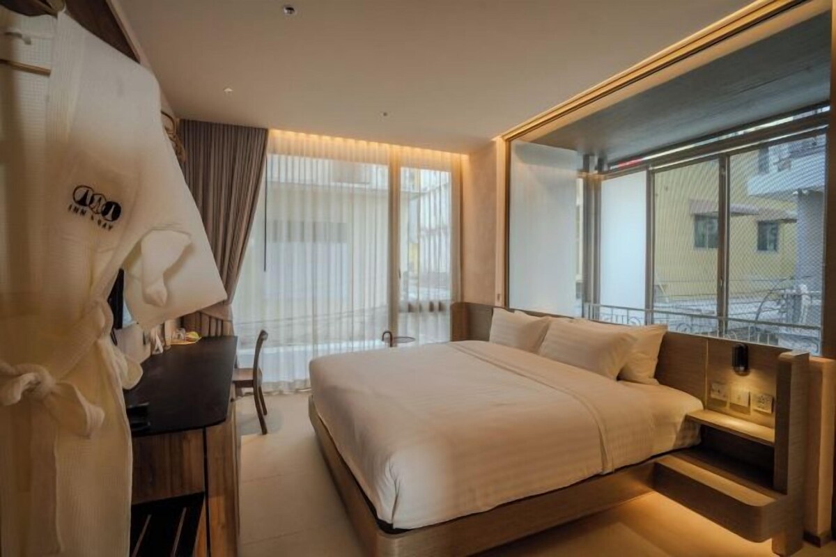 A hotel room with a large bed, a desk, and a window with a view of the city.