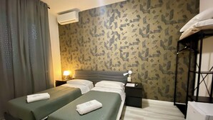 A hotel room with two single beds, a wardrobe, a desk, a lamp, and an air conditioning unit. - Guest House Pirelli (Milan)