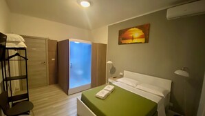 A hotel room with a bed, a wardrobe, a chair, a desk, and a painting on the wall. - Guest House Pirelli (Milan)