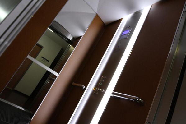 An elevator interior with a metallic handrail, a control panel with buttons, and a glass door. - Brit Hotel Confort Villeneuve Sur Lot (Bias)