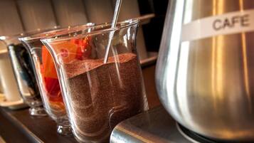 Une machine à café avec une étiquette indiquant « CAFÉ » et deux verres remplis d’un liquide brun, vraisemblablement du café.