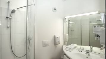 Un baño moderno con cabina de ducha de vidrio, un lavabo blanco con espejo y un perchero para toallas.