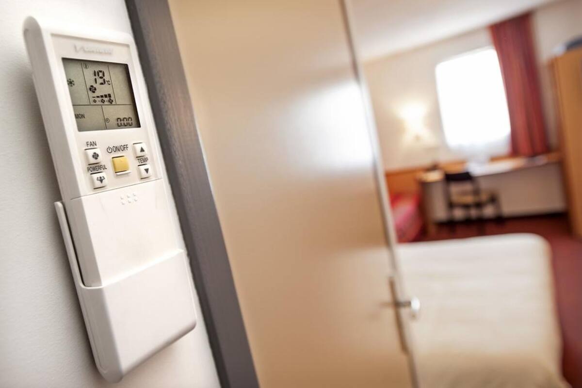 Ein Thermostat mit digitaler Anzeige, einer Funktion zur Lüftersteuerung und einer Taste zur Temperatureinstellung.