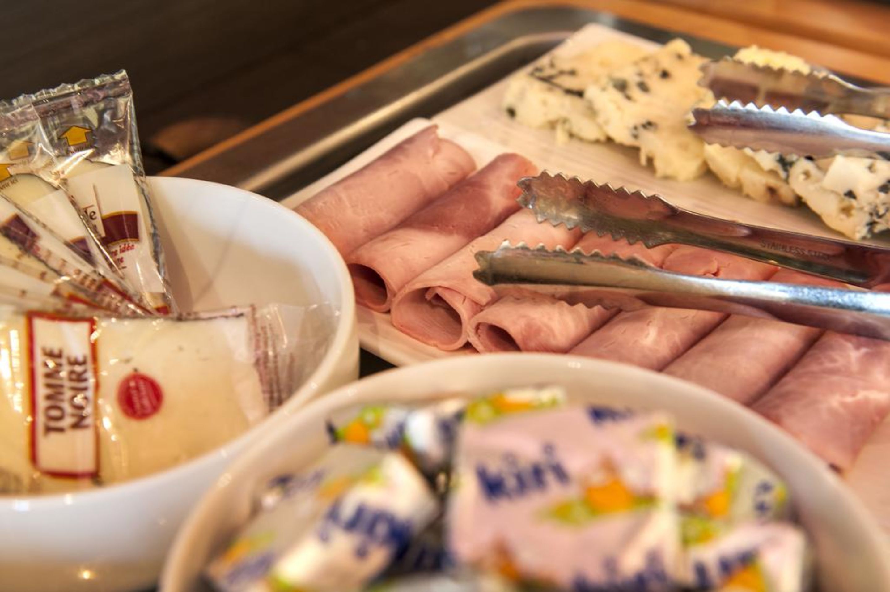 Un bufé con diversos alimentos, incluyendo carnes frías, quesos y snacks empaquetados.