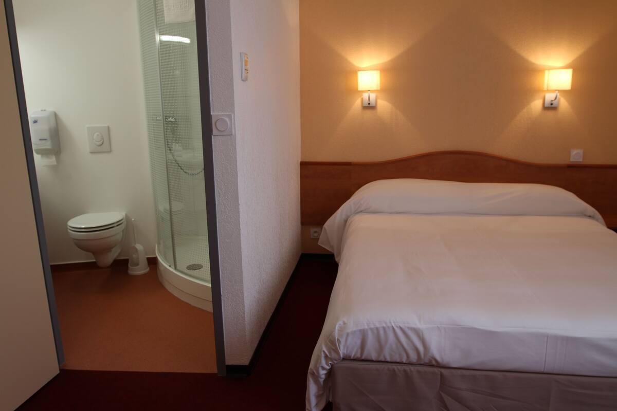 Ein Hotelzimmer mit Bett, Dusche und Toilette.