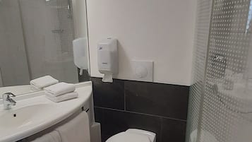 A bathroom with a white sink, a toilet, and a shower enclosure.