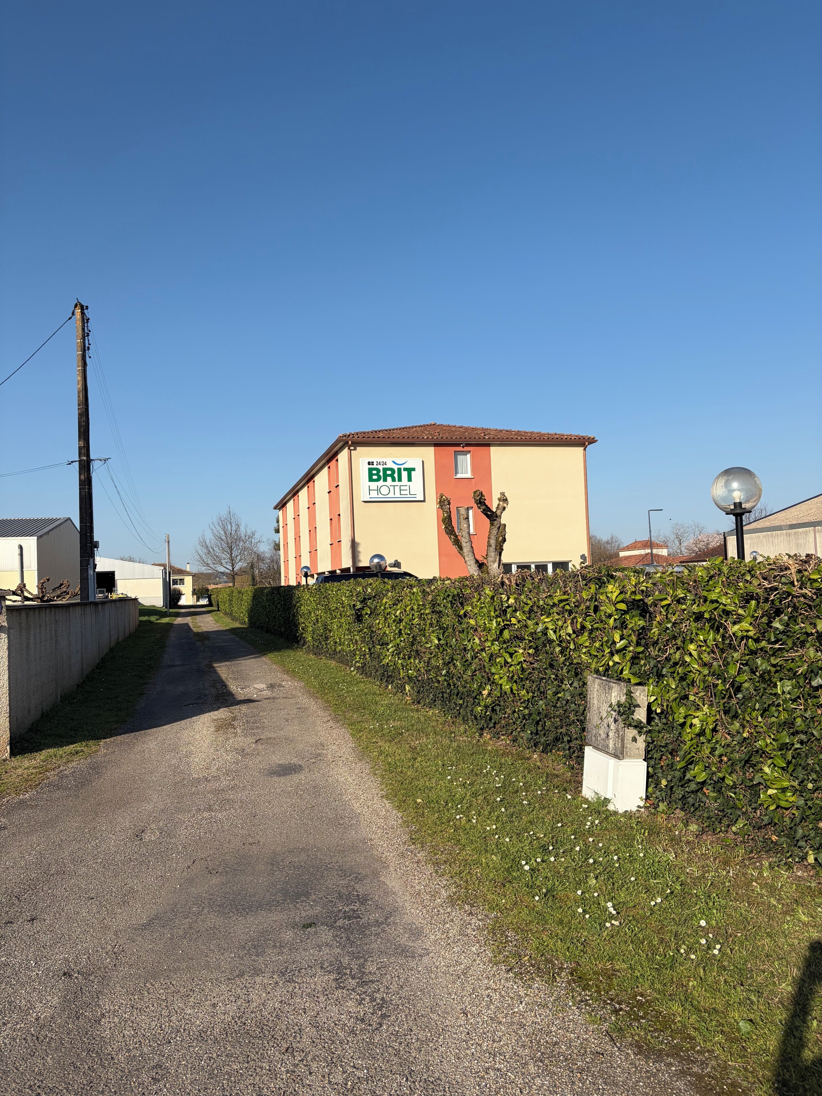 Un sendero de grava que lleva a un edificio con un letrero que dice 'BRIT HOTEL'.