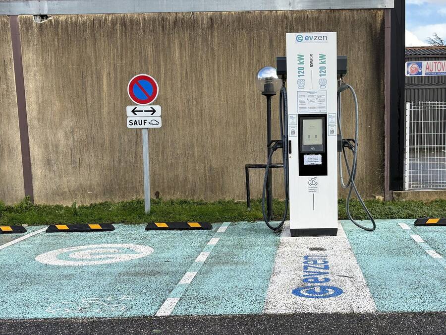 A charging station with a sign indicating a 120 kW EV charger, a no parking sign, and a directional arrow sign.