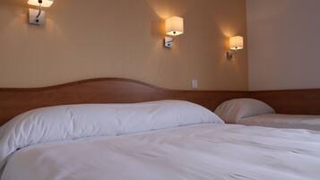 A hotel room with two beds, each with white linens, and wall-mounted sconces providing ambient lighting.