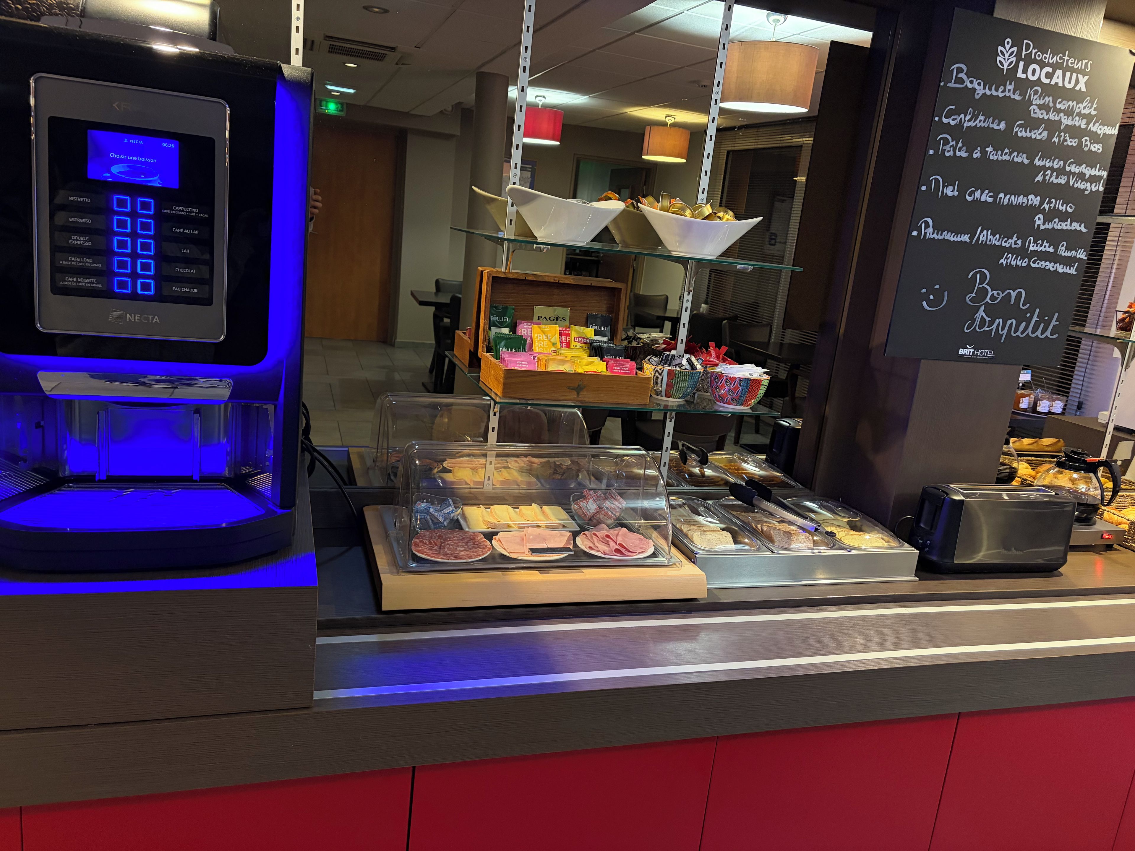 Une machine à café dotée d’un écran numérique, un présentoir en verre contenant divers produits alimentaires et un panneau affichant les options de plats et de boissons disponibles.