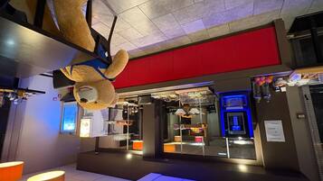 Een hotel lobby met een grote knuffelbeer decoratie, een rode wand en een automaat.