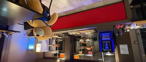 A hotel lobby with a large teddy bear decoration, a red wall, and a vending machine.