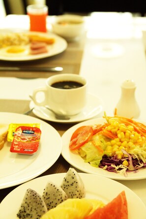 A breakfast table with plates of food, a cup of coffee, and condiments. - 101 Holiday Suite (Bangkok)