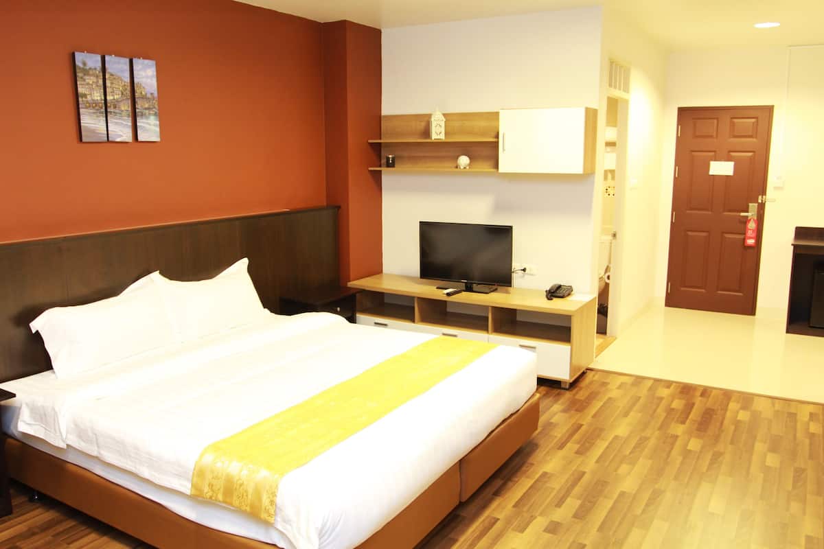 A hotel room with a large bed, a television, a small desk, and a door.