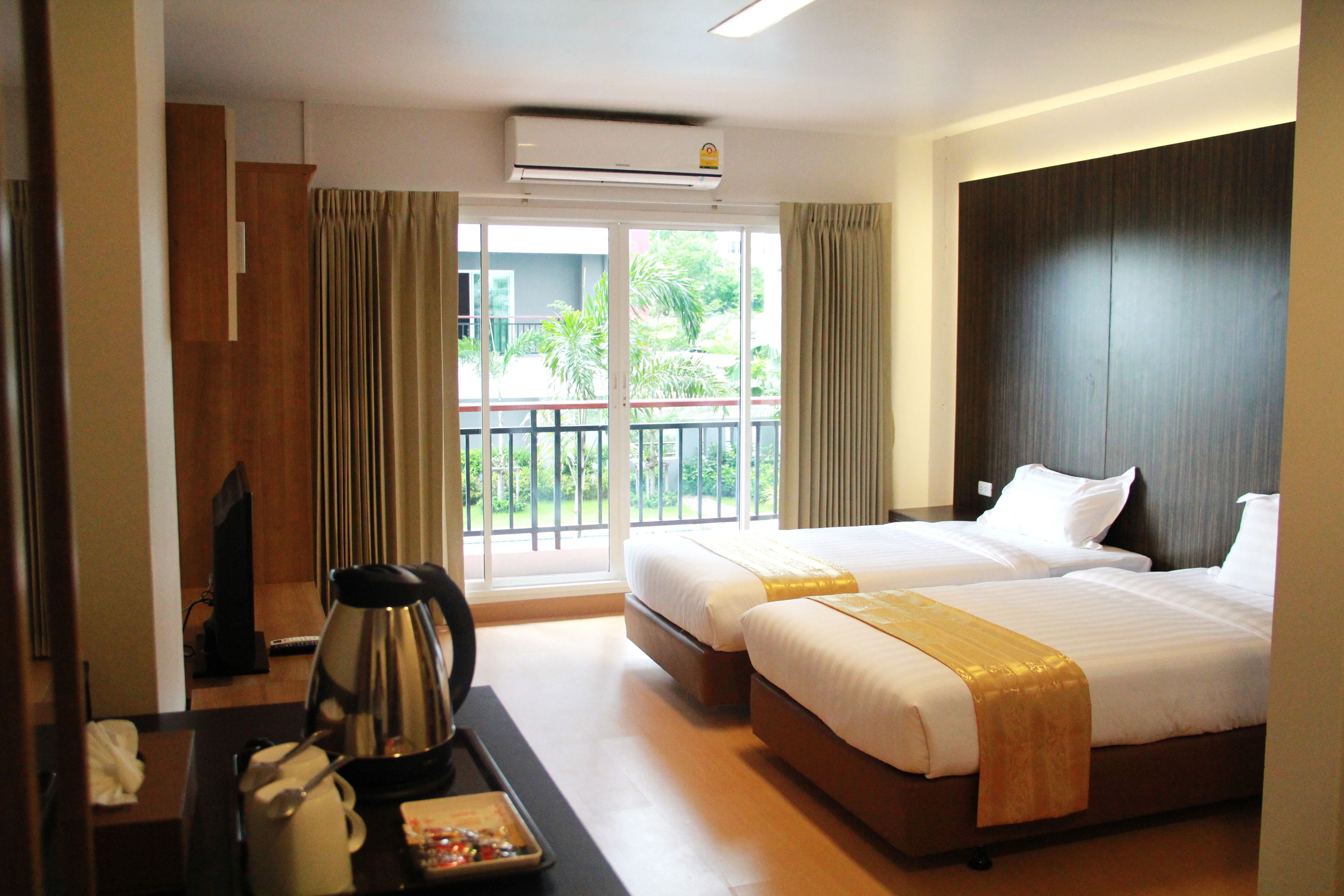 A hotel room with two beds, a coffee maker, a tray table, and a view of the outdoors.