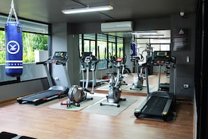 A gym with treadmills, elliptical machines, and a punching bag. - 101 Holiday Suite (Bangkok)