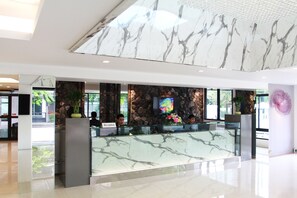 A reception area with a marble counter, a television, and a stone wall with plants. - 101 Holiday Suite (Bangkok)