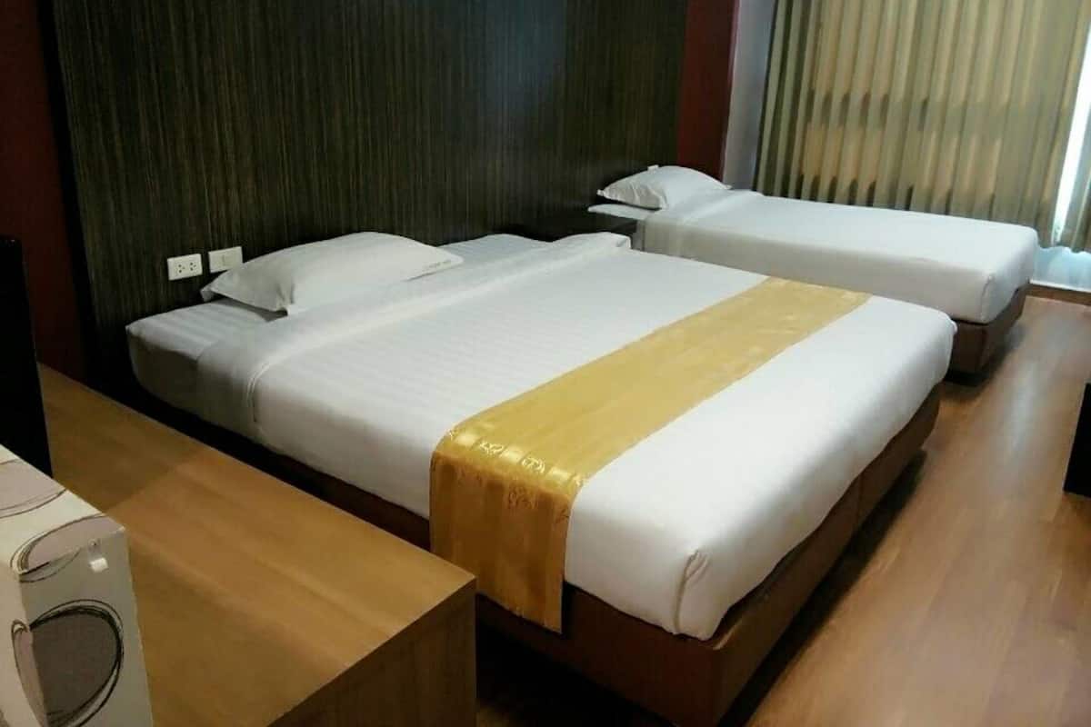 A hotel room with two beds, a wooden desk, and a dark-colored headboard.