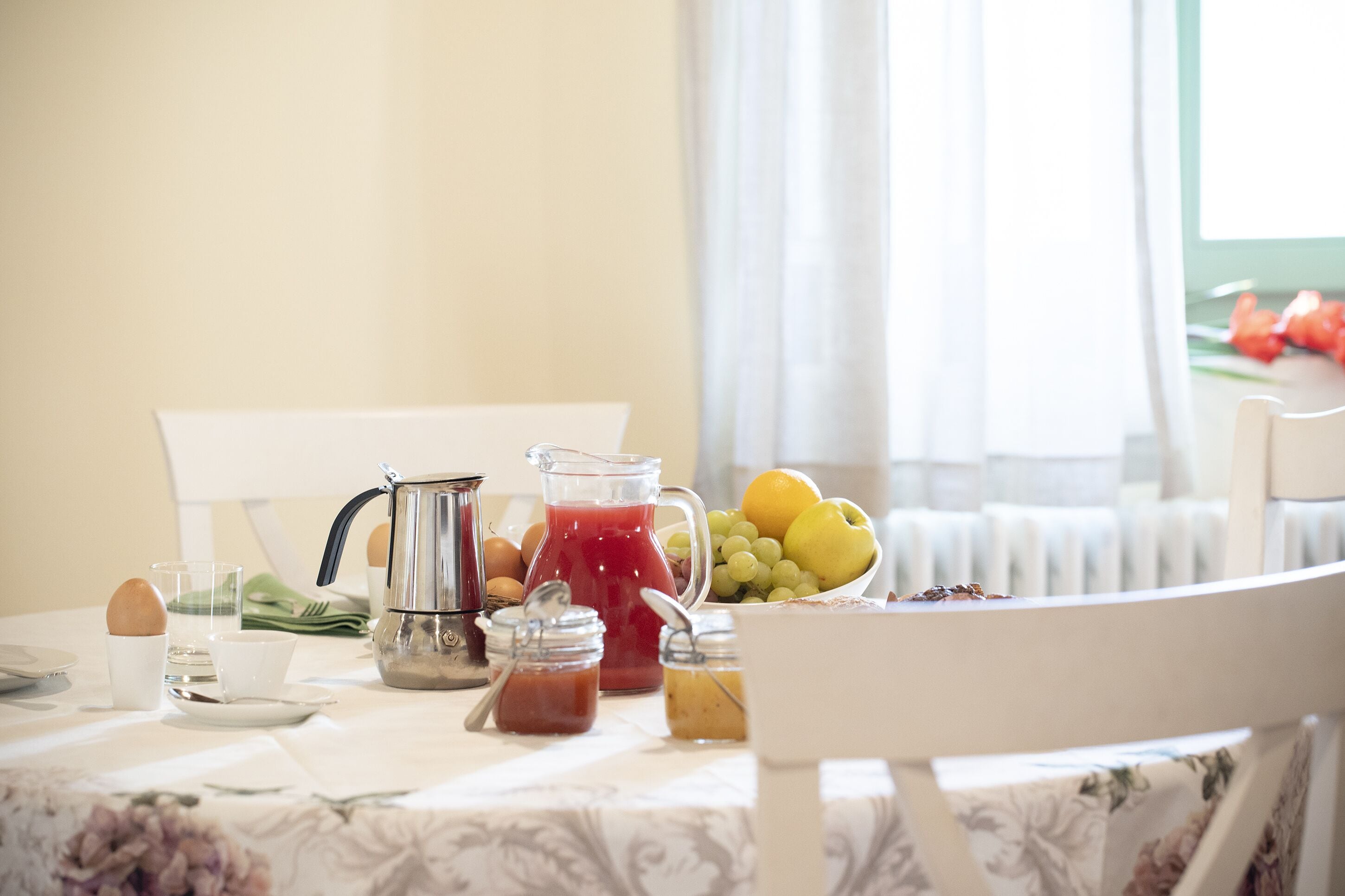 A breakfast table with a pitcher of red juice, a bowl of fruit, and various breakfast items.