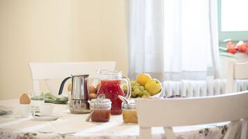 A breakfast table with a pitcher of red juice, a bowl of fruit, and various breakfast items.