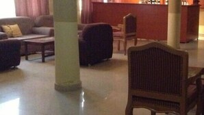 Un amplio salón con un conjunto de sofás, una silla de madera y una mesita.