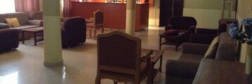 Un amplio salón con un conjunto de sofás, una silla de madera y una mesita.