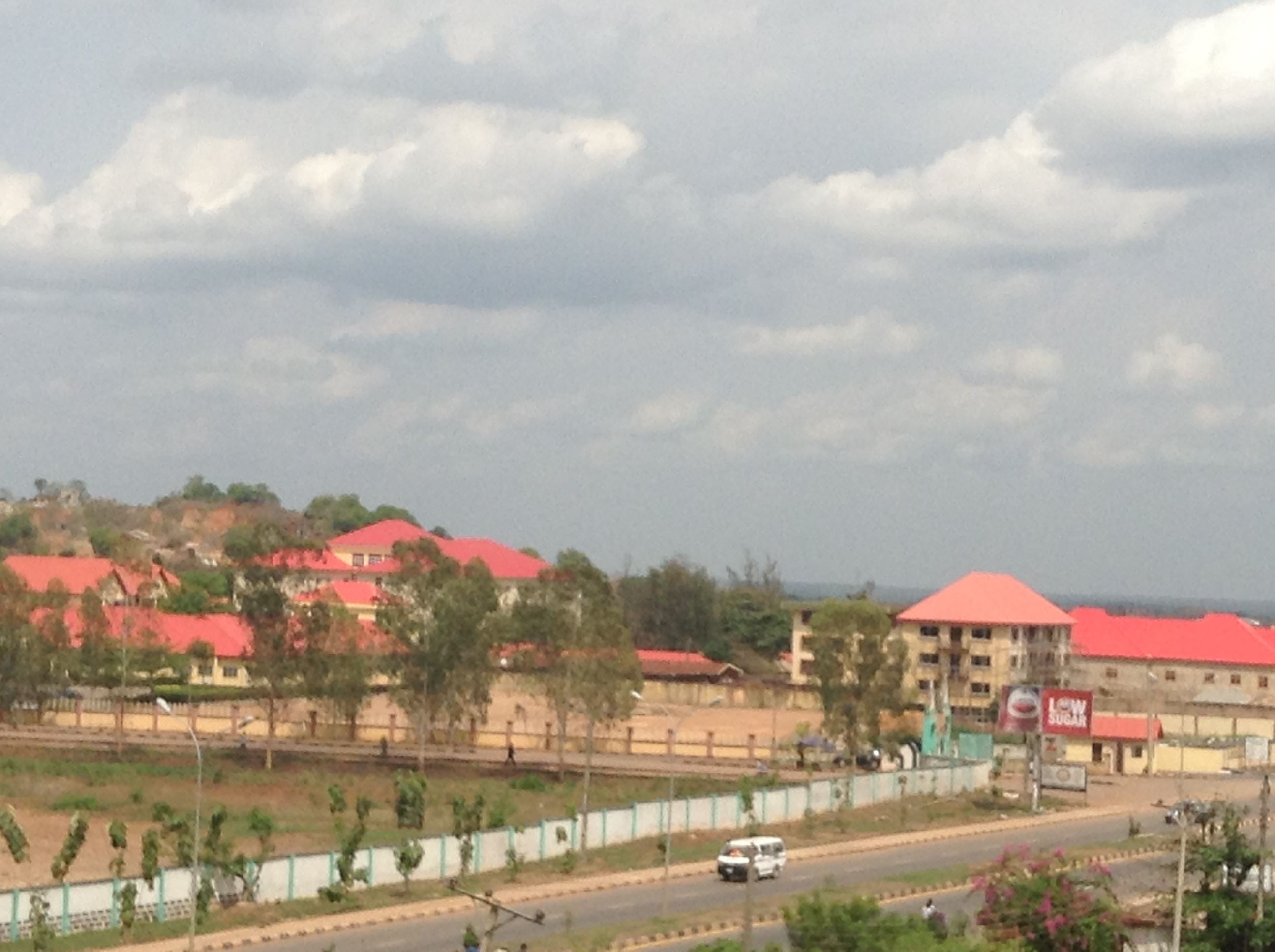 A view of a town with buildings, roads, and a cloudy sky.