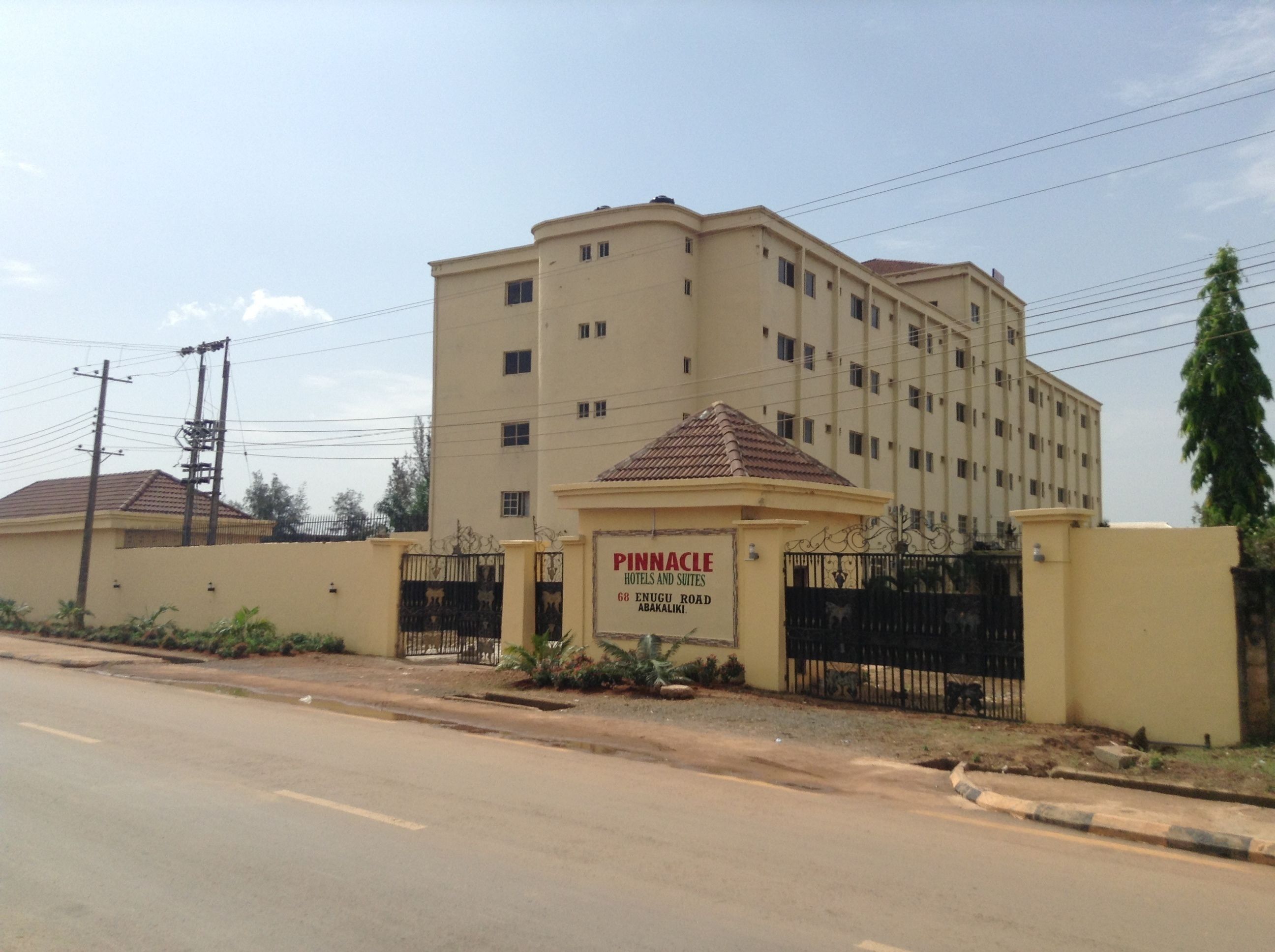 Ein mehrstöckiges Hotel mit einem Schild, das Pinnacle Hotels and Suites anzeigt, gelegen in der Enugu Road 68, Abakaliki.