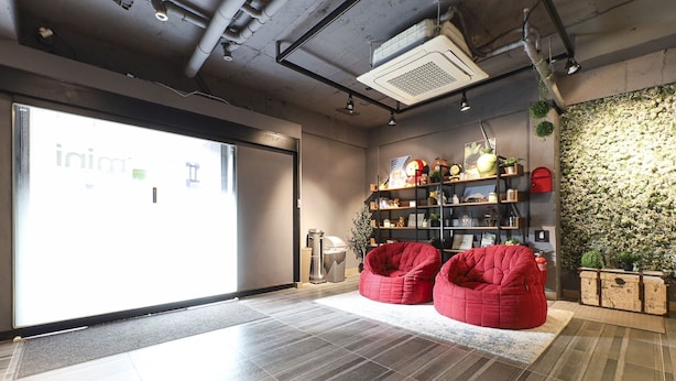 Ein modernes Interieur mit einer großen Glasdoor, roten Sitzsäcken und einer Wandpflanzenwand.