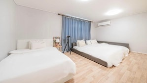 Ein modernes Hotelzimmer mit zwei Betten, einer Stehlampe und einem großen Fenster mit Vorhängen.