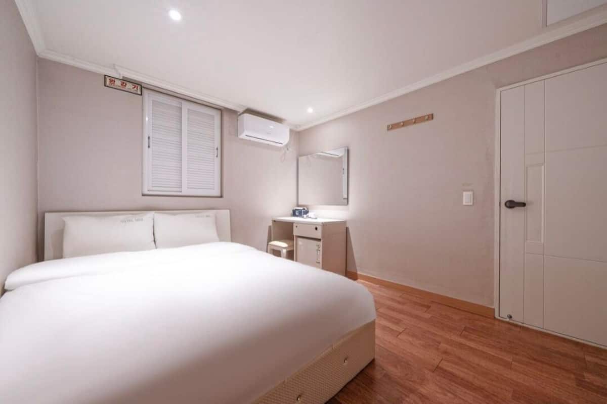 A bedroom with a bed, a bedside table, a mirror, and a wardrobe.